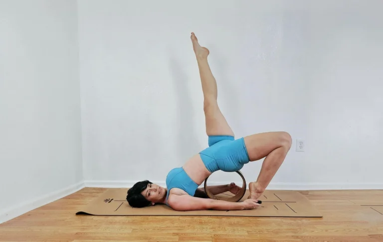 A person practicing advanced yoga on a non toxic cork yoga mat with alignment lines, using a yoga wheel for a backbend.
