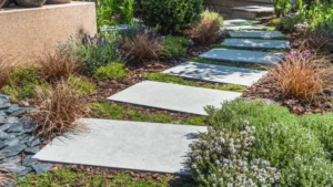 Modern rectangular concrete stepping stones forming a pathway through a lush garden with ornamental plants.
